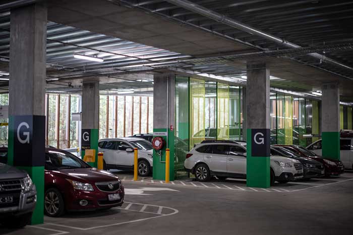 Cars are parked in the interior of  multi level Belgrave Station  car park. Concrete pillars have letter G to indicate this is ground floor level 