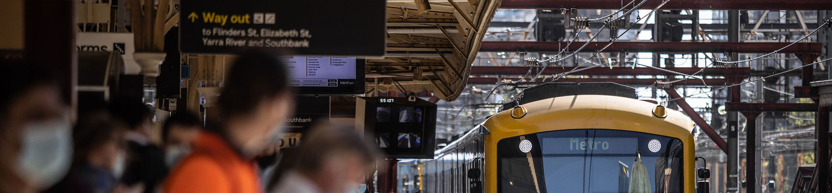 Commuters standing on a platform as a train arrives.