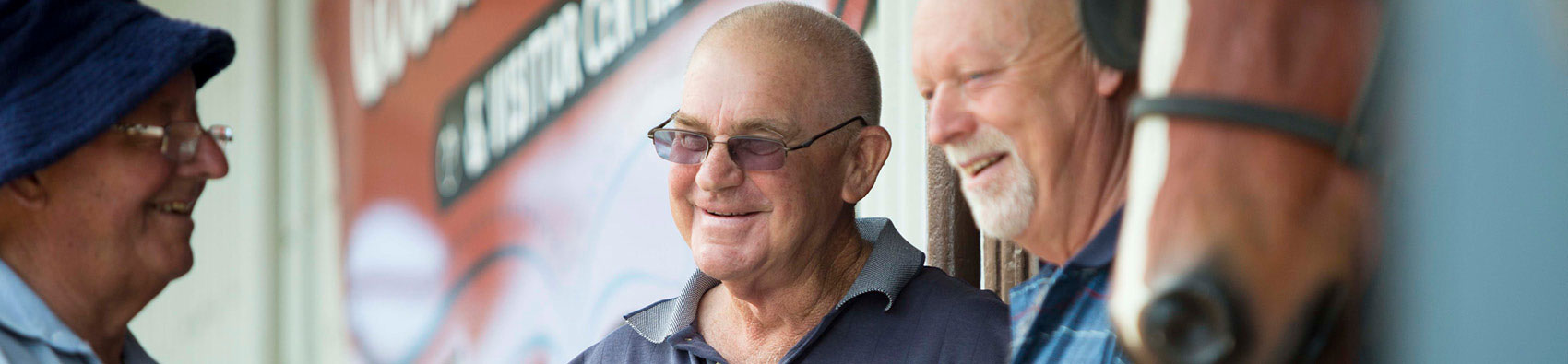 Three people and a horse standing outside a community building.