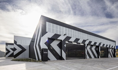External view of Bendigo Tramways storage facility. Building is painted black and white. W Class trams can be seen inside the facility.