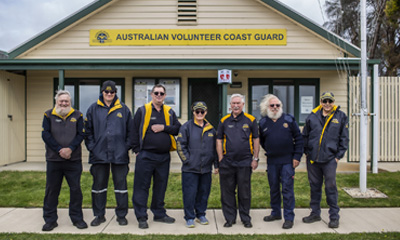 A group of 7 people standing in front of the headquarters of the Queenscliff Volunteer Coast Guard. 
